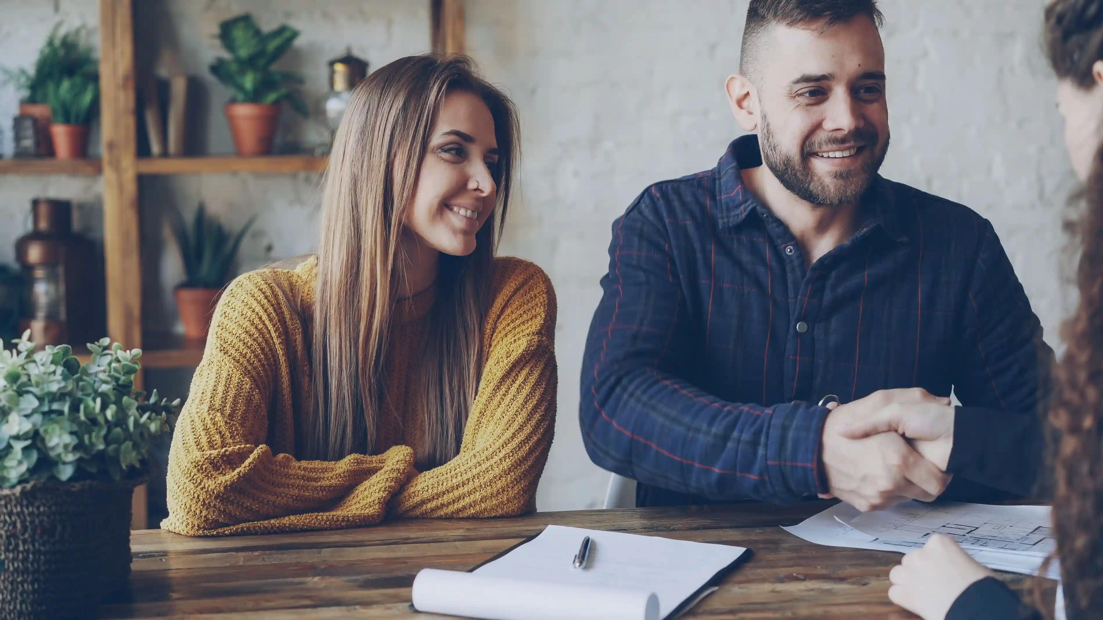 Poignée de main entre une courtière et ses clients souriants